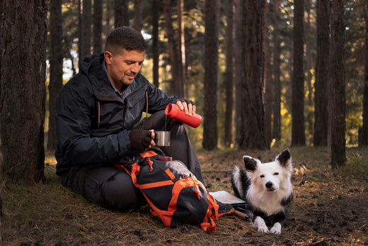 man giving water to a dog while hiking in the woods