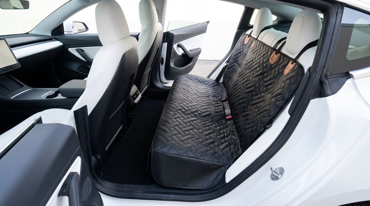 A dog seat cover installed over the pale interior of an electric car